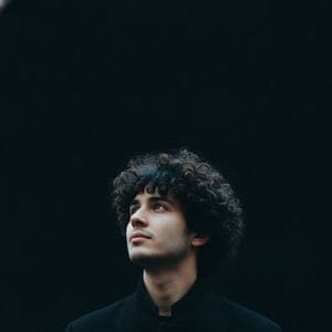 A man in a black coat photographed at night