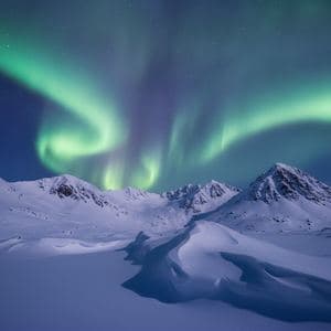 The northern lights over a snowy mountain range