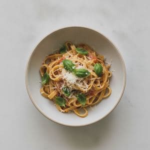 A bowl of pasta on a plain white surface