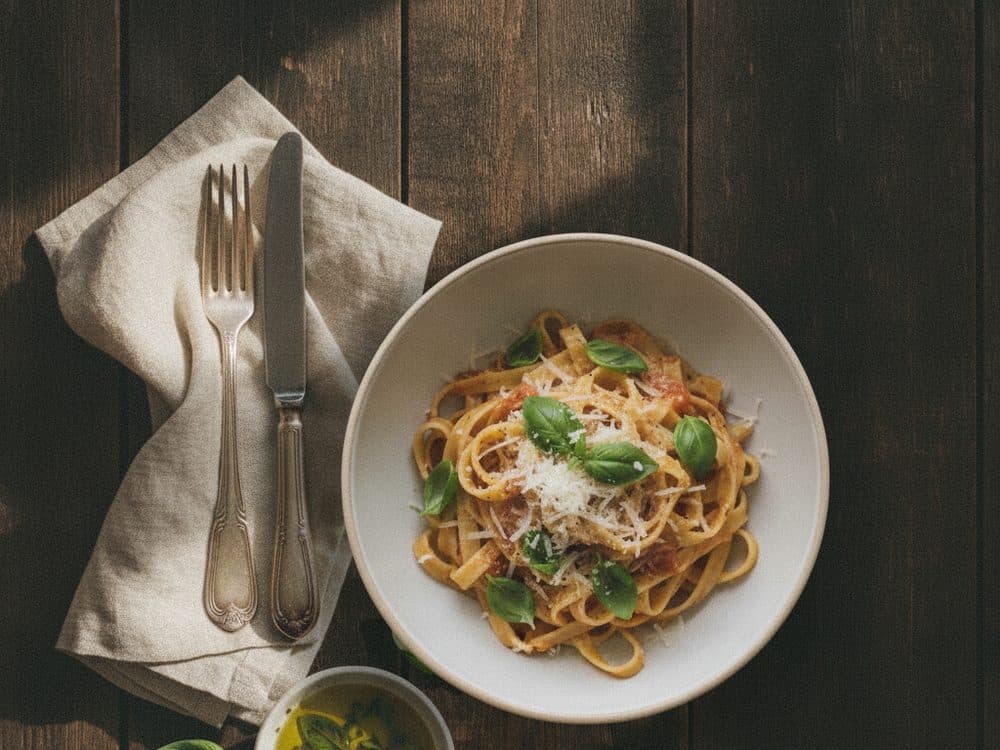 A bowl of pasta styled on a rustic wooden table, shot from above