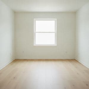 An empty living room with bare white walls and oak floors