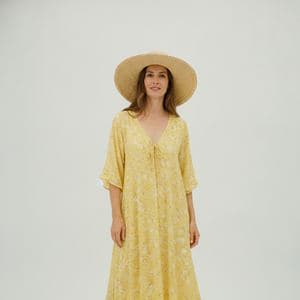 A woman in a yellow summer dress on a plain background